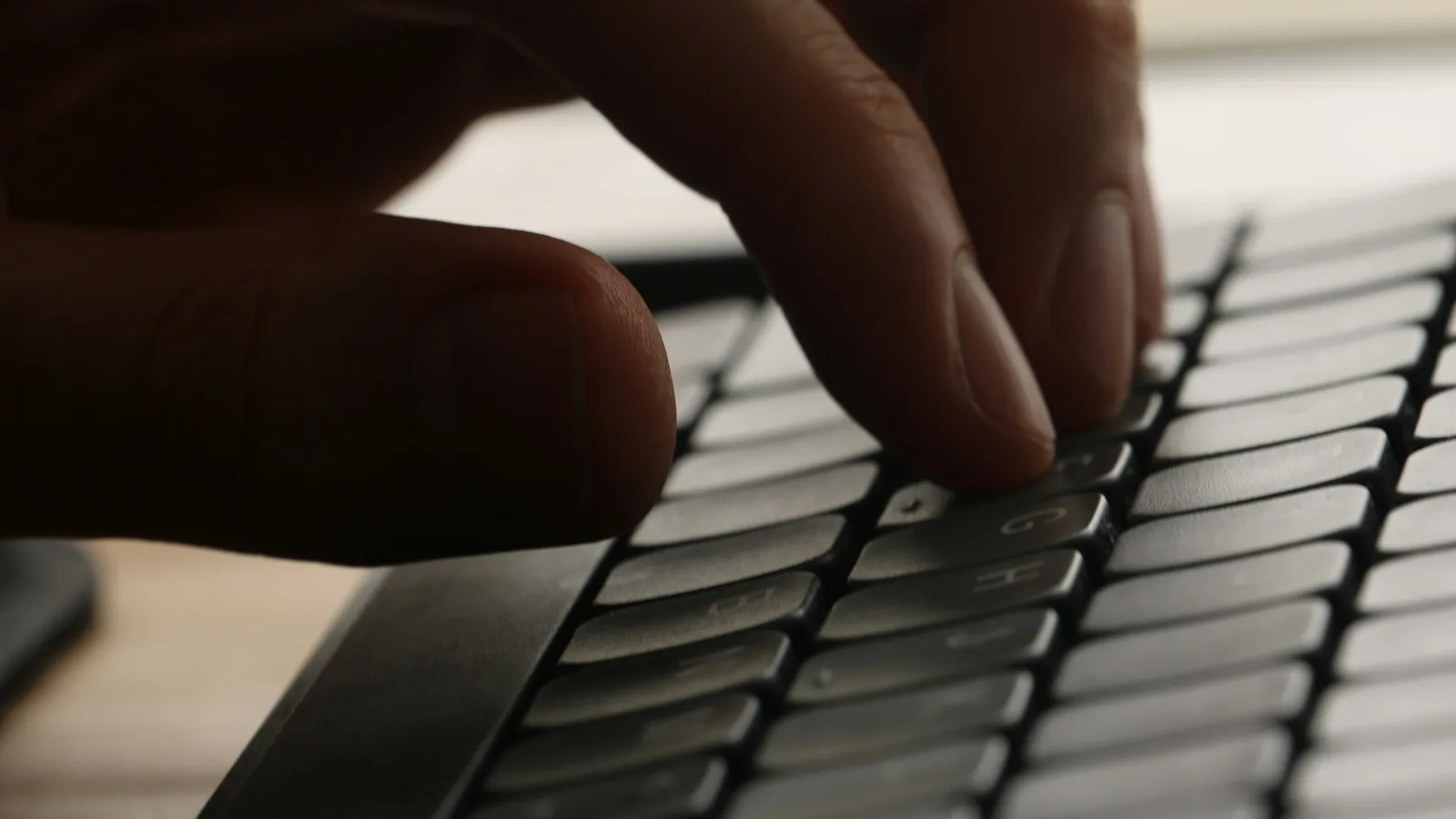 Close-up of a hand typing on a laptop keyboard